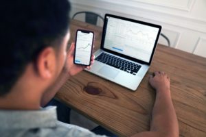 Ein Mann sitzt vor dem Laptop und schaut sich Forex-Währungskurse an.